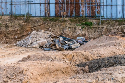 Construction site with debris, scaffolding, and piles of dirt under a blue sky, in South Korea