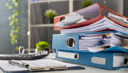 Overfilled folders on an office desk with calculator and biros, symbol of bureaucracy, AI