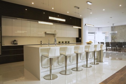Quartz countertop island with white leather and stainless steel barsrools in spacious kitchen