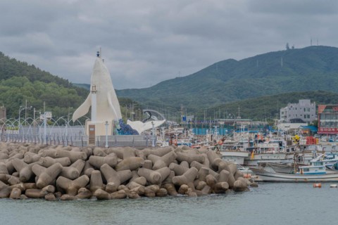Harbor view with a white lighthouse, docked boats, and tetrapod breakwater, in Ulsan, South Korea,