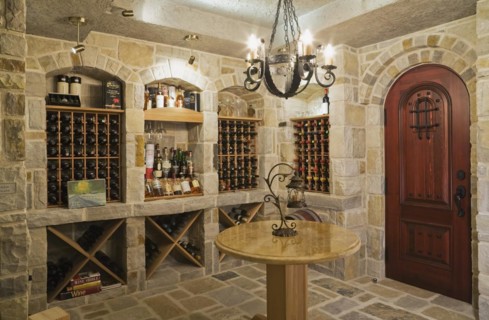 Medieval style beige and tan cut stone wine cellar in basement inside elegant style home, Quebec,
