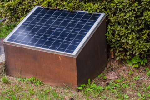 Closeup of small solar panel in front of green shrubbery in South Korea