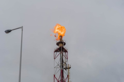 Flaring gas burns at the top of an industrial stack against a gloomy sky, in Ulsan, South Korea,