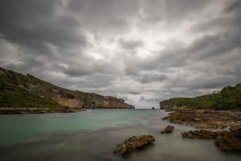 Rocky coast, long bay by the sea at sunset. Dangerous view of the Caribbean Sea. Tropical climate