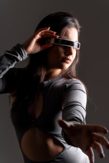 Studio portrait with grey background of a sensual futuristic woman using virtual reality goggles
