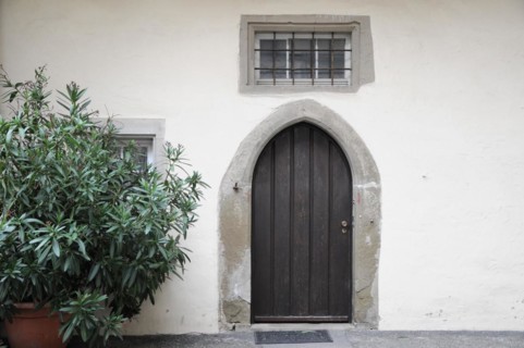 Langenburg Castle, entrance area with a wooden arched door, a small window and a potted plant,