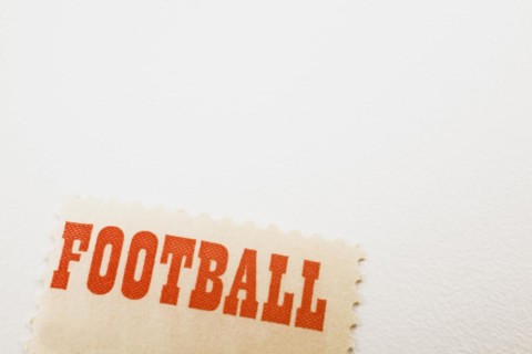 Close-up of the word Football printed in bold red letters on commemorative postage stamp on white