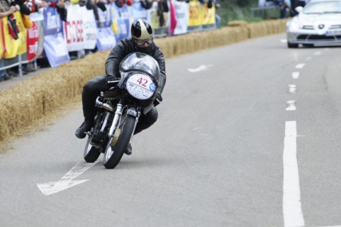 A motorbike racer concentrates on the race track, spectators in the background, SOLITUDE REVIVAL