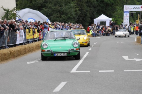 A green Porsche 911 drives on a street during an event, SOLITUDE REVIVAL 2011, Stuttgart,