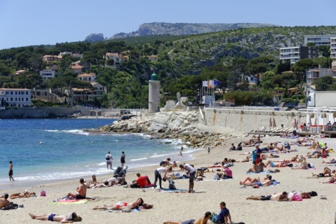The bay of Port Miou in Cassis, people sunbathing on the beach with a view of the sea and nature,