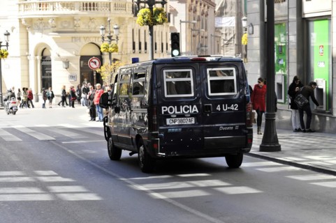 Granada, Police vehicle in a busy city street with pedestrians and shops, Andalusia, Spain, Europe