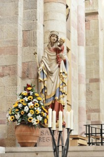 Speyer Cathedral, Colourful sculpture of a saint with child, surrounded by flowers and candles,