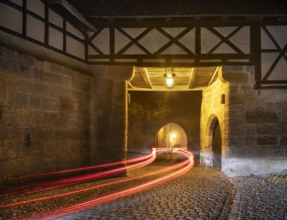 View through the Spitaltor at dusk in fog, traces of light from a car, Rothenburg ob der Tauber,