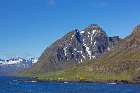 Rugged mountains and orange lighthouse at Skalanes along the fjord Seyoisfjoerour, Seydisfjoerdur