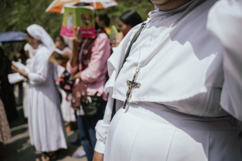 A nun wears a Cross as she recite prayers during a re-enactment of the crucifixion of Jesus Christ