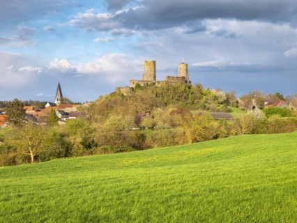 View of Muenzenberg town and castle in the Wetterau under dark clouds in spring evening light,