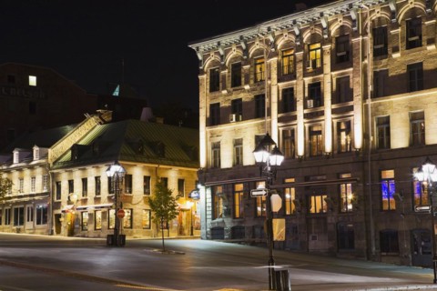 Old architectural style commercial and residential buildings illuminated at night on deserted Place