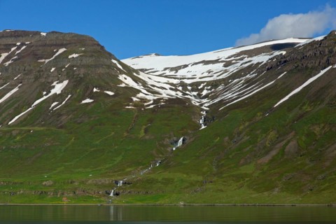 Waterfall and desolate farm along the fjord Seyoisfjoerour, Seydisfjoerdur in summer, Eastern