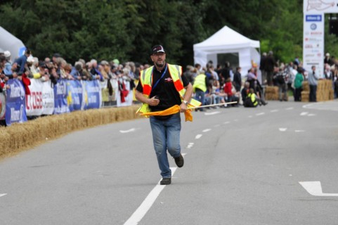 A person in a yellow safety waistcoat runs across a race track with a flag, SOLITUDE REVIVAL 2011,