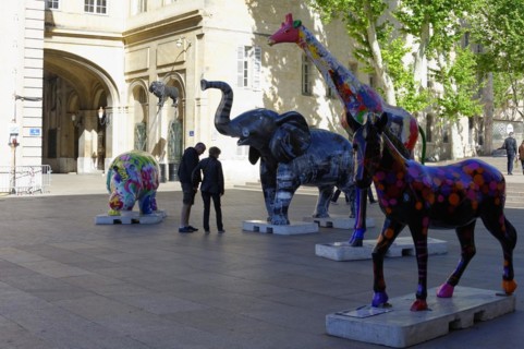 Colourful elephant sculptures on a square with people strolling in the background, Marseille,