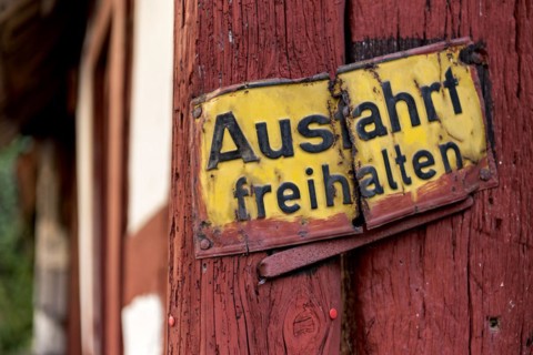 Old sign, keep exit clear, bent and rusty on wooden beam, courtyard exit, historic half-timbered