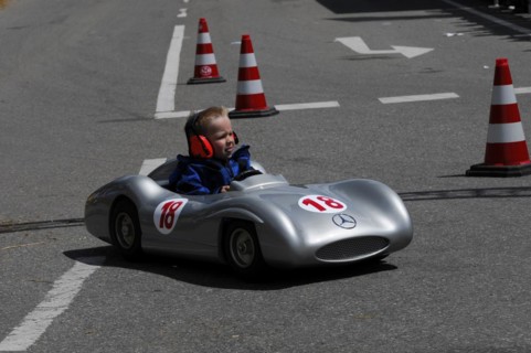 Smiling child enjoying a ride in a silver soapbox on a closed-off road, SOLITUDE REVIVAL 2011,