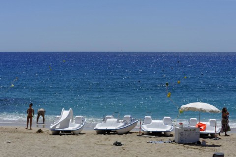 The bay of Port Miou in Cassis, A sunny beach day with people, sunbathing boats and clear blue sea,