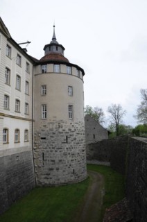 Langenburg Castle, A medieval tower on a castle wall surrounded by trees under a cloudy sky,
