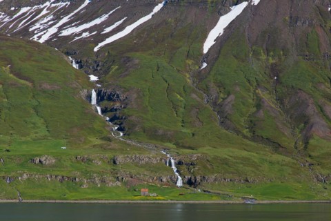 Waterfall and desolate farm along the fjord Seyoisfjoerour, Seydisfjoerdur in summer, Eastern