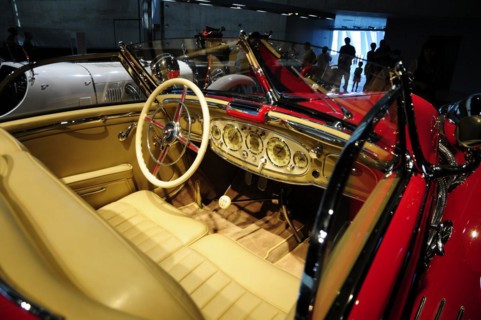 View into the cockpit of a classic red vintage car with stylish steering wheel and fittings,