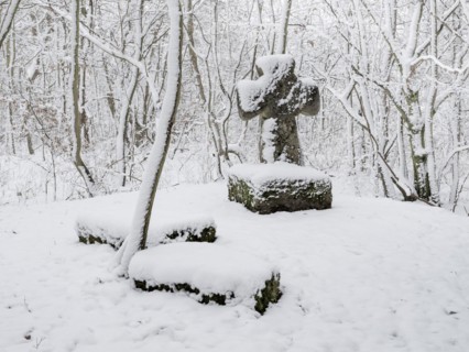 Medieval stone cross in a snow-covered forest in winter, murder cross, atonement cross, Freyburg