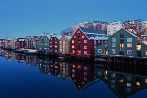 Historic warehouse buildings reflected in the river Nidelva at dusk, Bryggene, Trondheim, Norway,