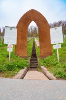A rust-coloured metal gate marks the entrance to a staircase leading through a vineyard, Jesus