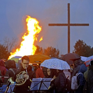 Musicians with a double horn in front of the Easter bonfire on the Haniel spoil tip with the summit