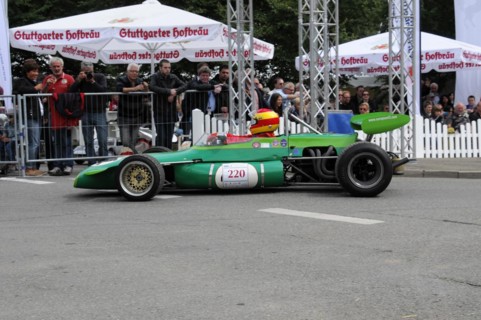 Green Formula racing car with number 220 on the race track in front of a crowd of spectators,