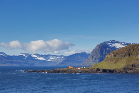 Rugged mountains and orange lighthouse at Skalanes along the fjord Seyoisfjoerour, Seydisfjoerdur