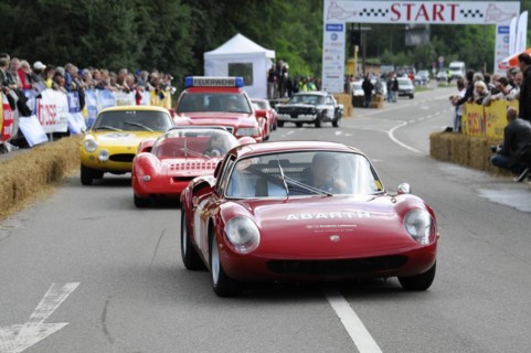 A red Abarth racing car drives on a road race track with spectators on the side, SOLITUDE REVIVAL