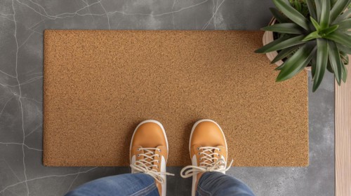 Blank welcome mat and pair of feet at front door of house. generative AI, AI generated