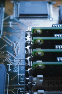 Close-up of blue and green lighted electronic computer circuit board with memory chip and lines,