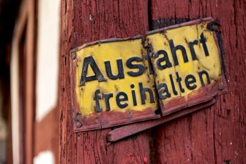 Old sign, keep exit clear, bent and rusty on wooden beam, courtyard exit, historic half-timbered