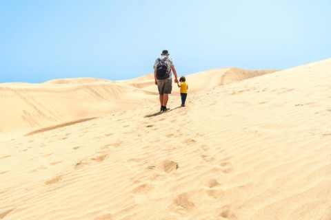 Father and son on vacation laughing running in the dunes of Maspalomas, Gran Canaria, Canary
