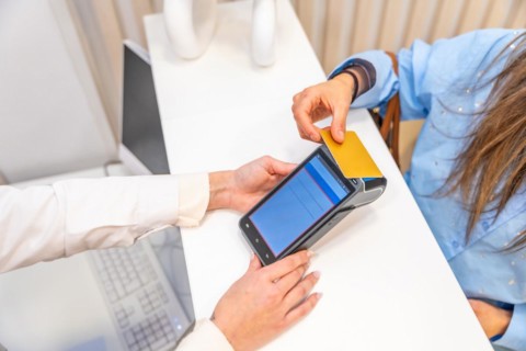Top view of an unrecognizable woman paying with credit card in a beautician clinic