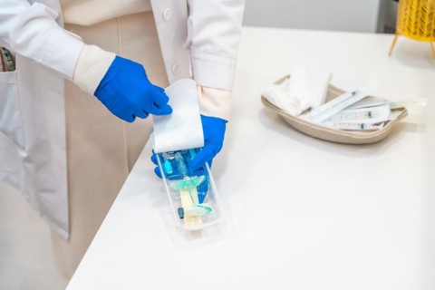Top view photo of a surgeon with protective blue latex gloves preparing a hyaluronic acid injection
