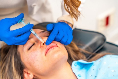 Close-up of a caucasian adult woman getting a Botox injection in the lips in a beautician