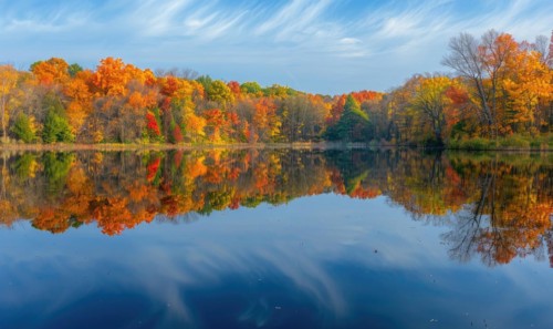Autumn foliage reflected in the calm waters of the lake, nature background AI generated
