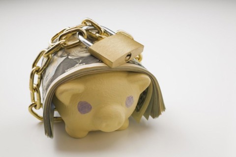 Close-up of wad of US currency bank notes wrapped with a brass chain and lock around a painted