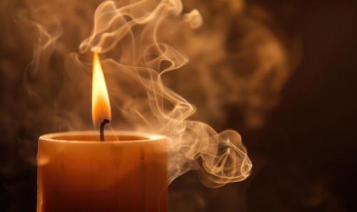 Close-up of a candle with wisps of smoke rising from the flame AI generated