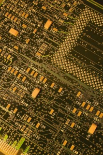 Close-up of dark green and golden yellow lighted electronic computer circuit board with lines and
