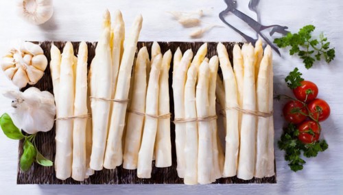 Neatly arranged bundles of asparagus on a board with garlic and tomatoes, AI generated, AI