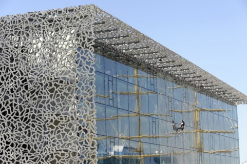Marseille harbour, window cleaner working on the extraordinary facade of a modern building,